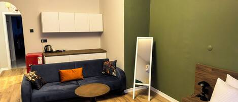 A modern living room with a sofa, a small round table, a bed, and a mirror.