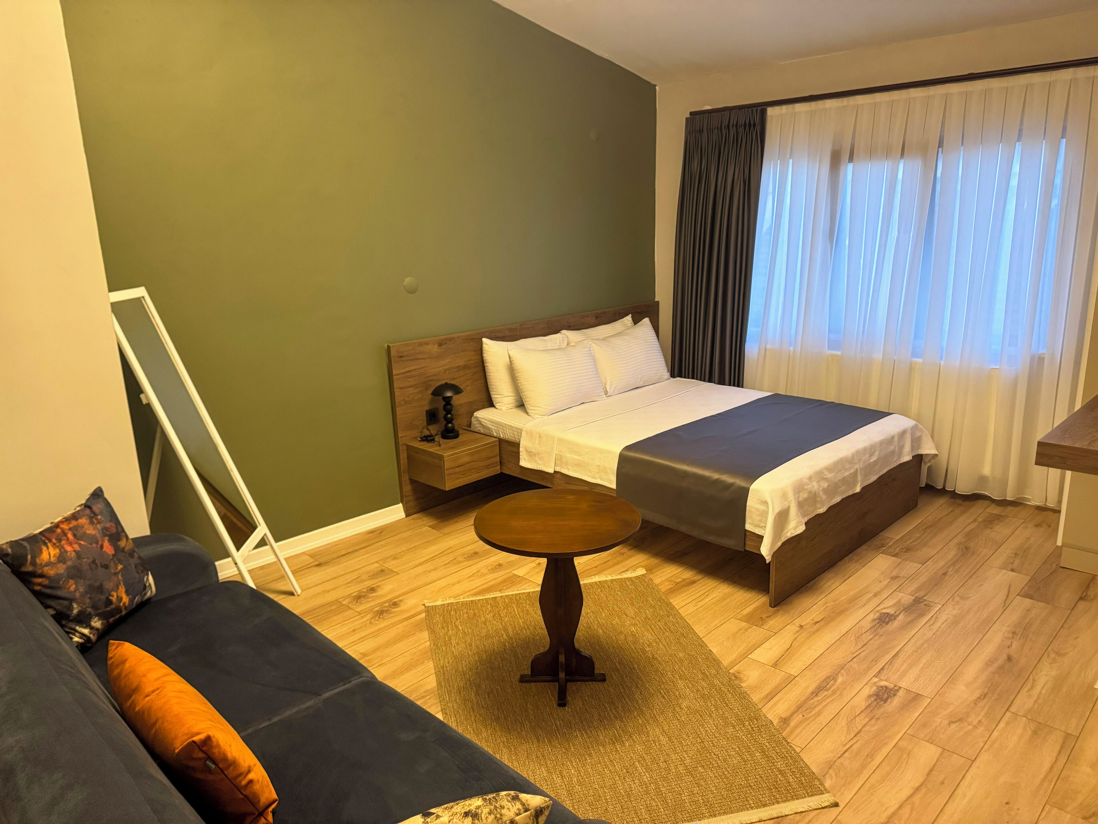 Una habitación de hotel con una cama, mesita de noche y una pequeña mesa redonda.