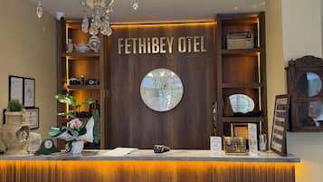 Ein Empfangsbereich mit einer Kandelaber, einer Uhr und einem Schild mit der Aufschrift 'FETHI BEY OTEL'.