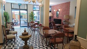 Un vestíbulo de hotel con mostrador de recepción, zona de estar y suelo estampado.