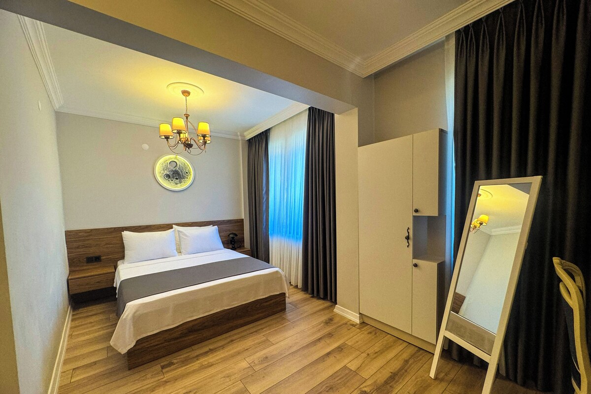 Een hotelkamer met een bed, een garderobe, een spiegel en een kroonluchter.