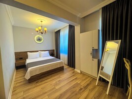 Habitación de hotel con cama, armario, espejo y candelabro.