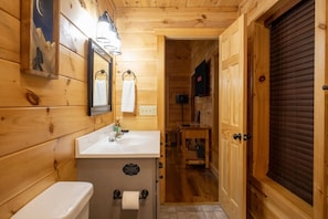 Un baño al estilo cabaña de madera con dos lavamanos, un inodoro y un espejo.