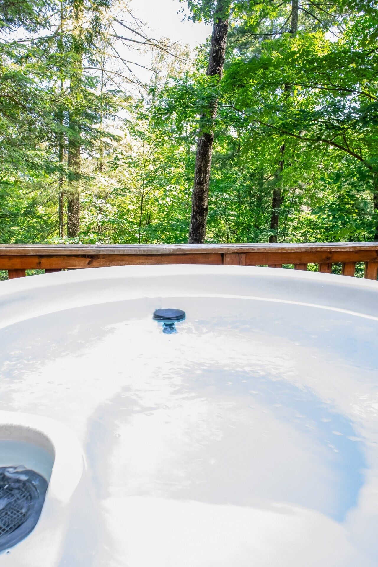 A hot tub in a forested area with a wooden deck.