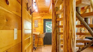 Interior de madera con una escalera, una zona de bar y un cartel que promociona actividades al aire libre.
