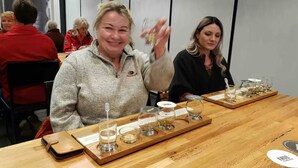 Une dégustation est organisée autour d’une table en bois où sont disposés différents verres et un plateau.