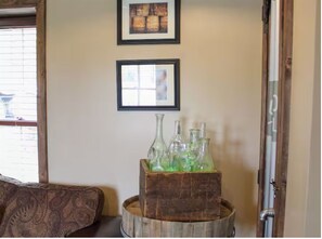 A room with a wooden barrel, a couch, and two framed pictures on the wall. - Buffalo Springs Distilling Company (Stamping Ground)