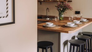 Eine Küche mit einer Holzinsel, schwarzen Hocker und einer Vase mit Blumen.