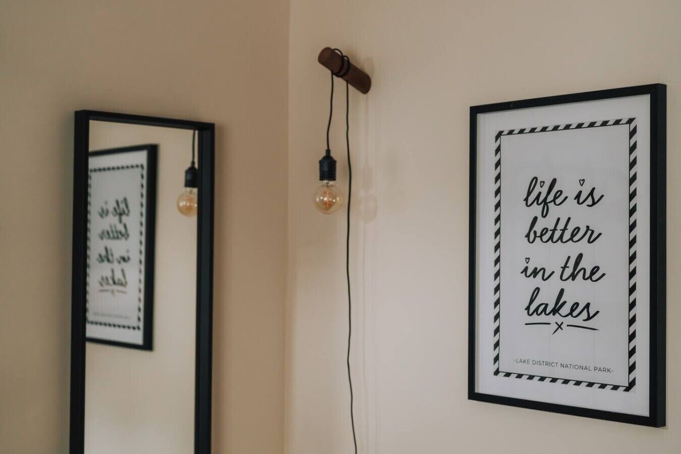 Two framed quotes on a wall, one with a quote about life being better in the lakes and the other with a quote in a different language.