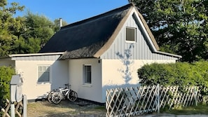 A house with a thatched roof, a white exterior, and a bicycle parked outside.