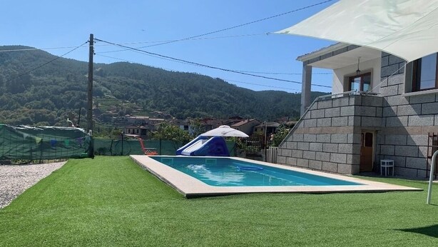 A swimming pool with a slide, a grassy area, and a building with a stone facade. - House with pool ribadavia (Francelos)