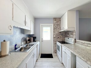 A kitchen with white cabinets, a granite countertop, a stove, and a dishwasher. - Alta Vida, Cozy Duplex Retreat (Sarasota)