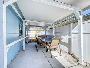 An outdoor patio with a table and chairs, a covered area, and a white fence. - Alta Vida, Cozy Duplex Retreat (Sarasota)