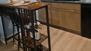 A compact kitchen with a wooden table, chairs, a microwave, and a clock on the wall.