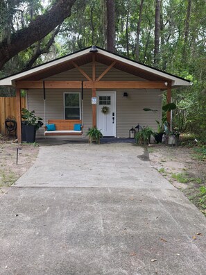A covered porch with a bench, a door with a wreath, and a 'No Pets Allowed' sign.