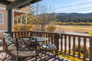 A covered outdoor seating area with a table and chairs, overlooking a scenic landscape with trees and hills. - Cozy 2-bedroom cabin in charming Big Bear Lake with AC (Big Bear Lake)