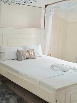 Ein Bett mit weißer Bettwäsche, einem Kopfteil und einem Baldachin.