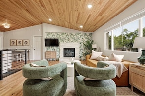 A living room with a fireplace, green armchairs, a sofa, and a TV. - Ferns & Foothills: Gateway Location, Family Friendly, Hot Tub / Backyard Games (Wheat Ridge)