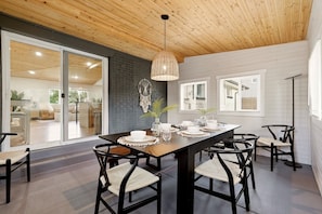 A dining area with a wooden ceiling, a table set for four, and black chairs with woven seats. - Ferns & Foothills: Gateway Location, Family Friendly, Hot Tub / Backyard Games (Wheat Ridge)