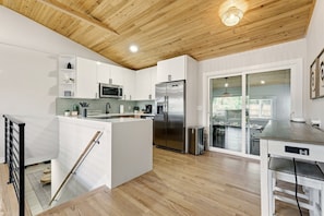 A modern kitchen with white cabinets, a stainless steel refrigerator, and a wooden ceiling. - Ferns & Foothills: Gateway Location, Family Friendly, Hot Tub / Backyard Games (Wheat Ridge)