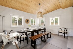 A dining area with a wooden ceiling, white walls, and large windows. - Ferns & Foothills: Gateway Location, Family Friendly, Hot Tub / Backyard Games (Wheat Ridge)