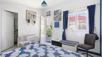 A bedroom with a bed, a chair, a window with curtains, and a door leading to another room.