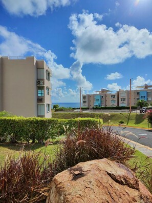 A modern building with multiple floors, a well-maintained lawn, and a clear view of the ocean. - TheTimeless Haven PR@ Oceanfront Escape- Maunabo (Maunabo)
