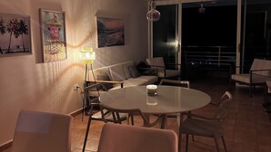 A dining area with a round table and chairs, a sofa, and a balcony with a railing. - TheTimeless Haven PR@ Oceanfront Escape- Maunabo (Maunabo)