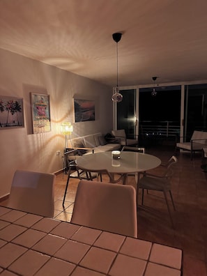 A dining area with a round table and chairs, a sofa, and a balcony with a railing. - TheTimeless Haven PR@ Oceanfront Escape- Maunabo (Maunabo)