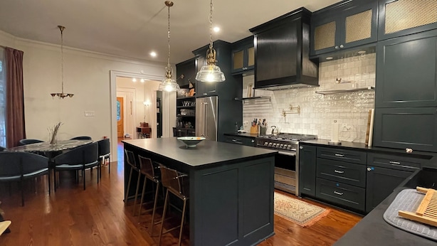 A modern kitchen with dark cabinetry, a central island, stainless steel appliances, and pendant lighting. - Charming, Spacious Victorian Near Downtown Dallas (Dallas)
