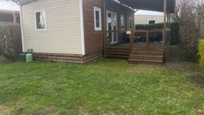 Ein Bungalow mit überdachter Veranda und kleinem Fenster.