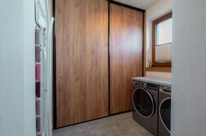 A laundry room with a washing machine, a dryer, and a wooden wardrobe. - Large Holiday Villa With Garden, Sauna and Jacuzzi (Brzeznica)