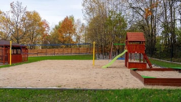 A playground with a sand area, a slide, and a wooden climbing structure.