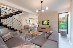 Una sala de estar moderna con una escalera, un comedor y un televisor.