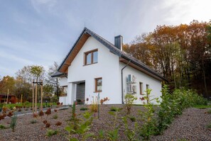 A modern house with a sloped roof, white exterior walls, and a gravel driveway. - Large Holiday Villa With Garden, Sauna and Jacuzzi (Brzeznica)