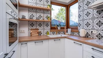 Et moderne køkken med hvide skabe, træbordplader og et mønstret backsplash.