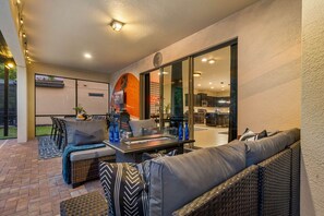 An outdoor patio with wicker furniture, a glass-top table, and a fire feature. - NEW! Star Wars Galactic Landing - Minutes to Disney World! Pool, Hot tub, Themed (Kissimmee)