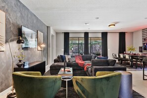 A modern living room with a sofa, chairs, a coffee table, and a dining area with a table and chairs. - NEW! Star Wars Galactic Landing - Minutes to Disney World! Pool, Hot tub, Themed (Kissimmee)