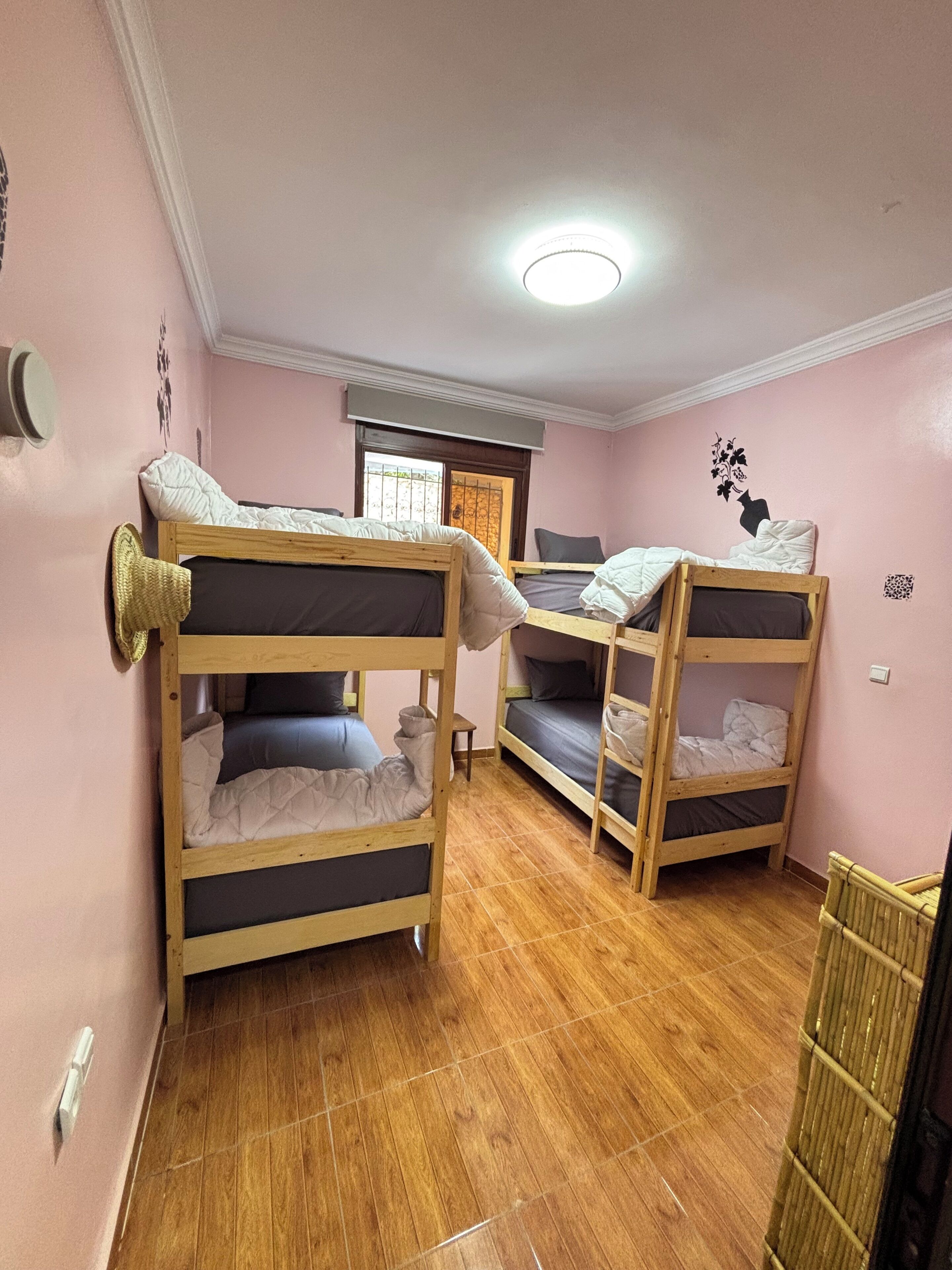 A room with bunk beds, a window with blinds, a radiator, and a wall decoration.