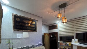 A living room with a sofa, a coffee table, a bookshelf, and a wall-mounted decorative item. - Tifawave surf stay tamraght (Tamraght)