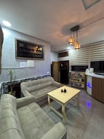 A living room with a sofa, a coffee table, a bookshelf, and a wall-mounted decorative item.