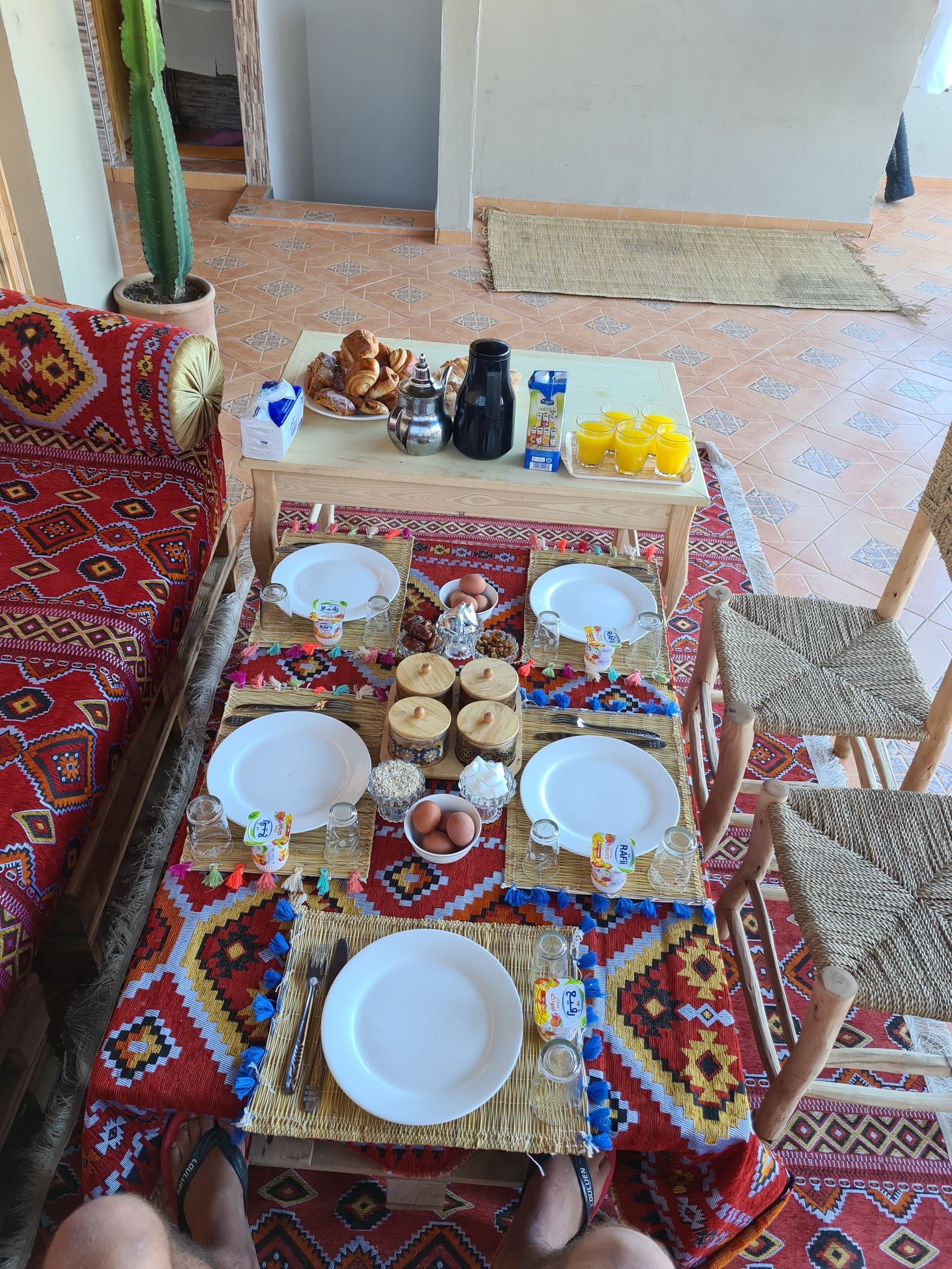 A breakfast setup with a table, chairs, and a patterned rug.