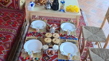 A breakfast setup with a table, chairs, and a patterned rug.