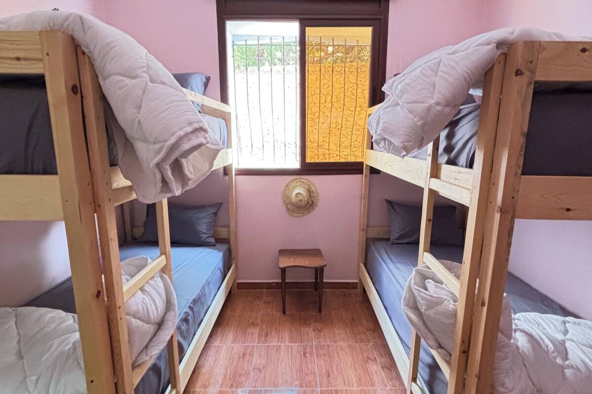 Habitación compacta con literas, un taburete pequeño y una ventana con vistas.
