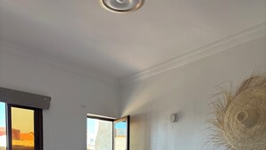A bedroom with a large bed, a window, a door leading to a balcony, and a wall-mounted light fixture. - Tifawave surf stay tamraght (Tamraght)