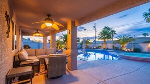 Un patio abrité avec une piscine, du mobilier d’extérieur et une vue sur des palmiers.