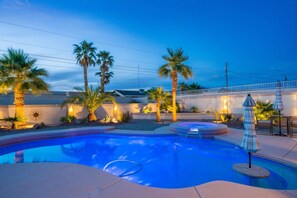 Une piscine bordée de palmiers, un jacuzzi et un espace salon extérieur.