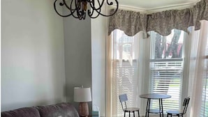 Una sala de estar con un sofá, una mesa y dos sillas, una lámpara y una luz decorativa en el techo.