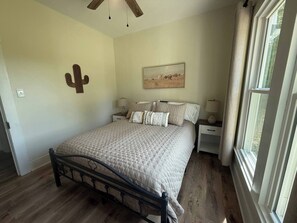 A bedroom with a bed, nightstands, a ceiling fan, a painting, and a window. - 3-bedroom farmhouse just minutes from Barkley Lake perfect for relaxing getaways (Marion)