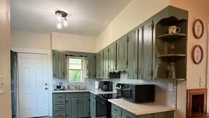 A kitchen with green cabinets, a microwave, a coffee maker, and a window. - 3-bedroom farmhouse just minutes from Barkley Lake perfect for relaxing getaways (Marion)